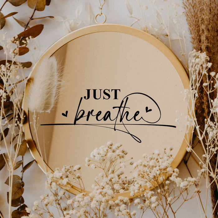 Black “Just Breathe” vinyl sticker on a round mirror with dried flowers