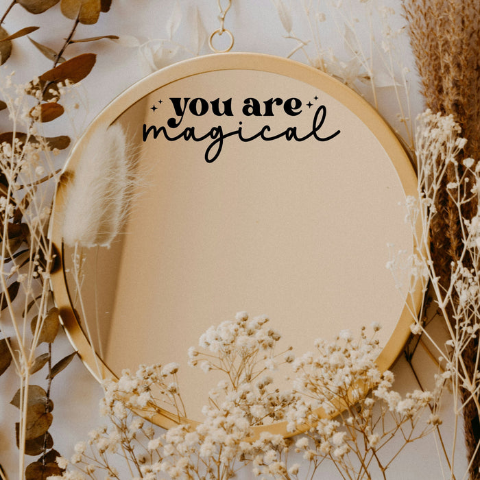 Black “You Are Magical” vinyl sticker on a round mirror with dried flowers
