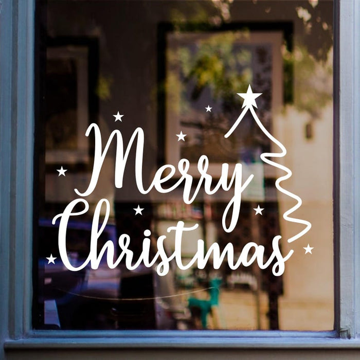 White Merry Christmas window sticker featuring handwritten lettering, an outlined Christmas tree and scattered stars displayed on glass.