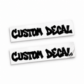 Two matching black custom text vinyl decals in bold graffiti lettering on backing sheets against white.