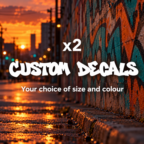 White graffiti lettering advertising two custom decals in your choice of size and colour against an urban wall at sunset.