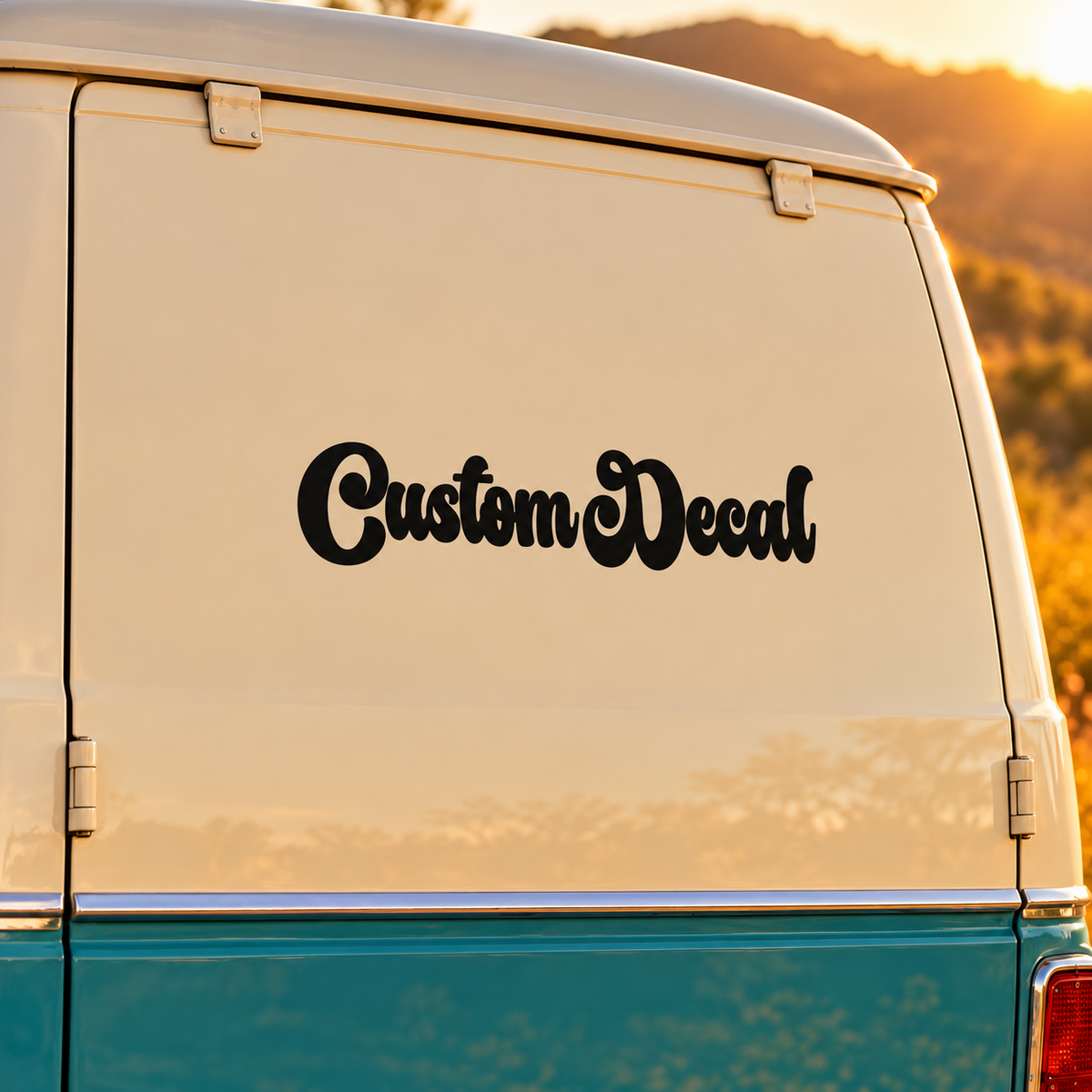 Black Custom Decal retro script lettering applied to the rear of a cream and teal campervan at sunset.