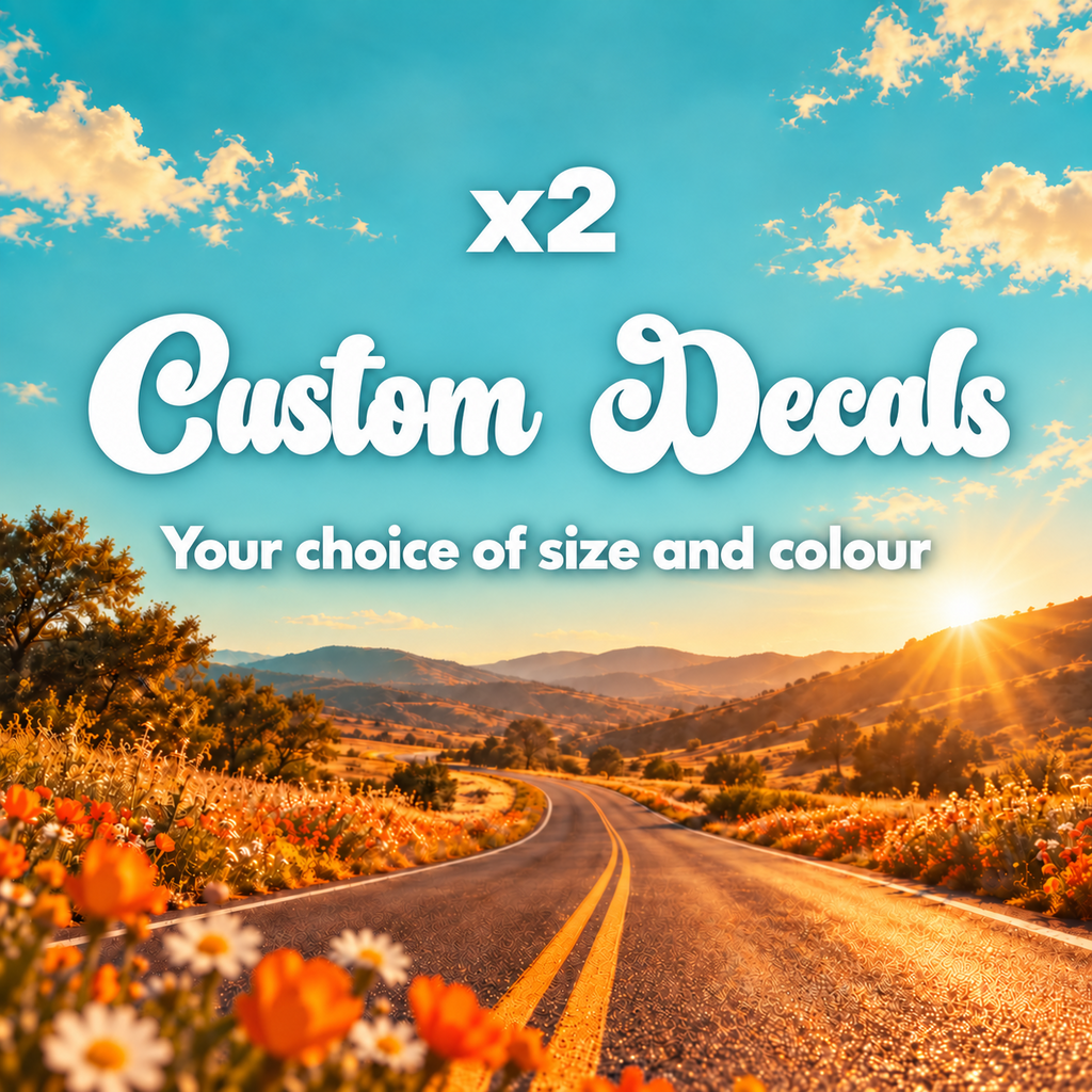 Two white retro script custom decals advertised in your choice of size and colour above a sunny road with orange wildflowers.