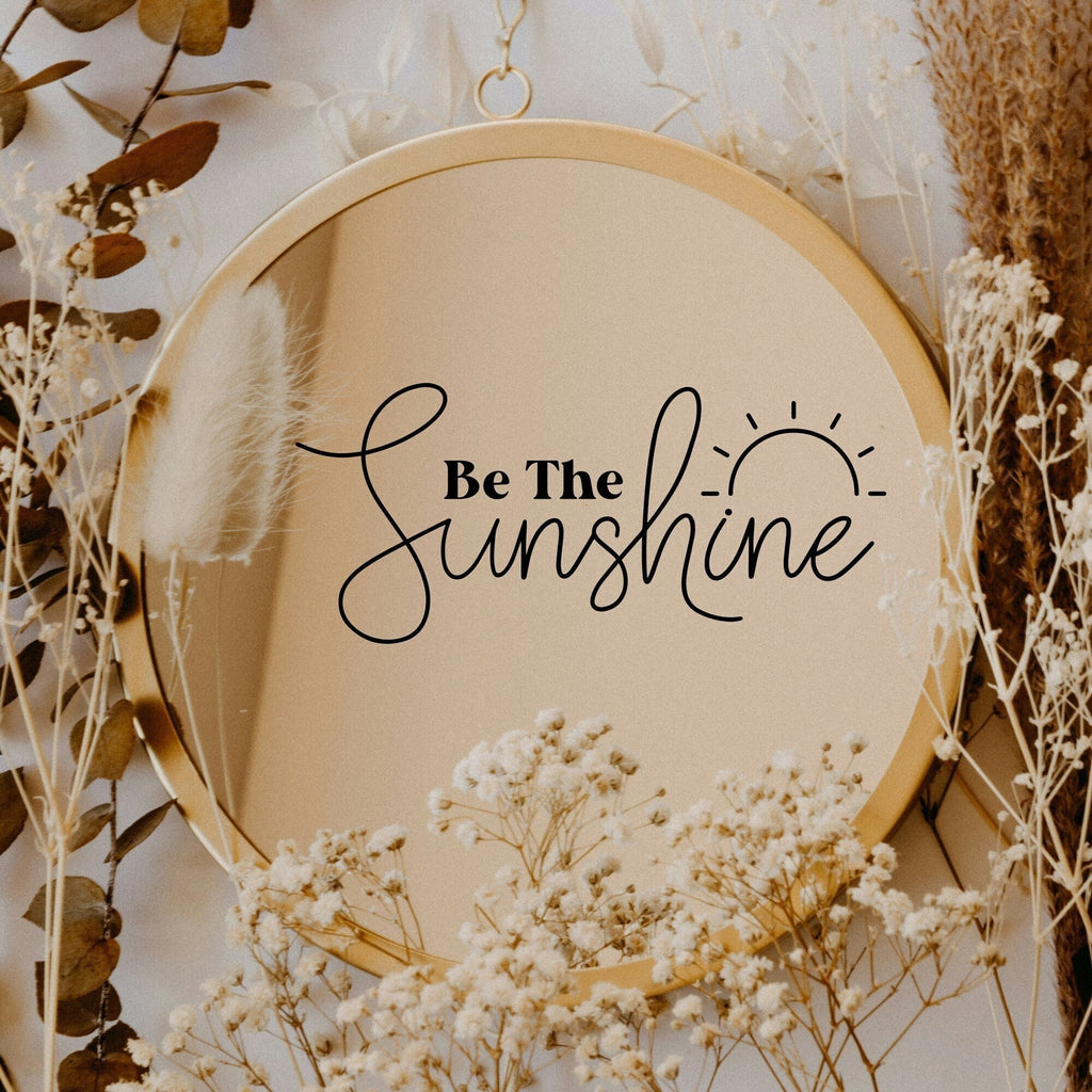 Black “Be The Sunshine” vinyl sticker on a round mirror with dried flowers