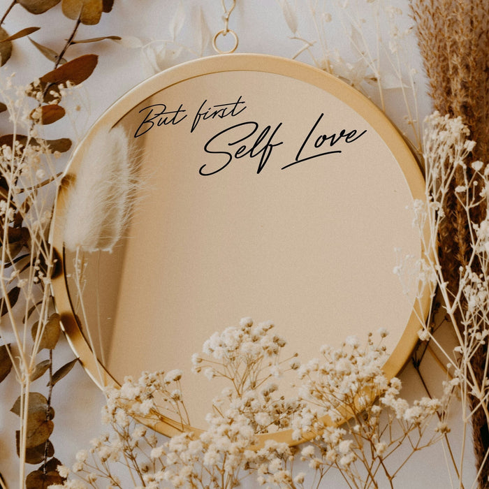 Black “But First Self Love” vinyl sticker on a round mirror with dried flowers