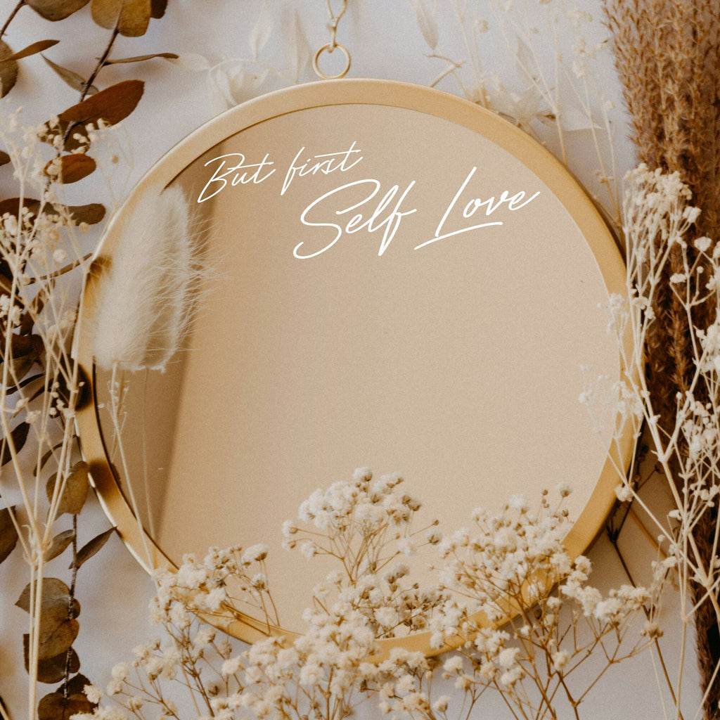 White “But First Self Love” vinyl sticker on a round mirror with dried flowers