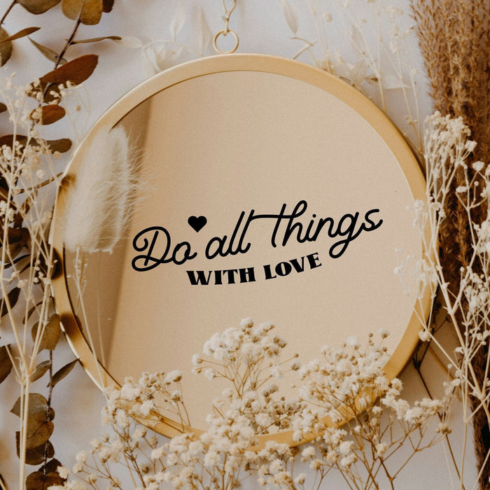Black “Do All Things With Love” vinyl sticker on a round mirror with dried flowers