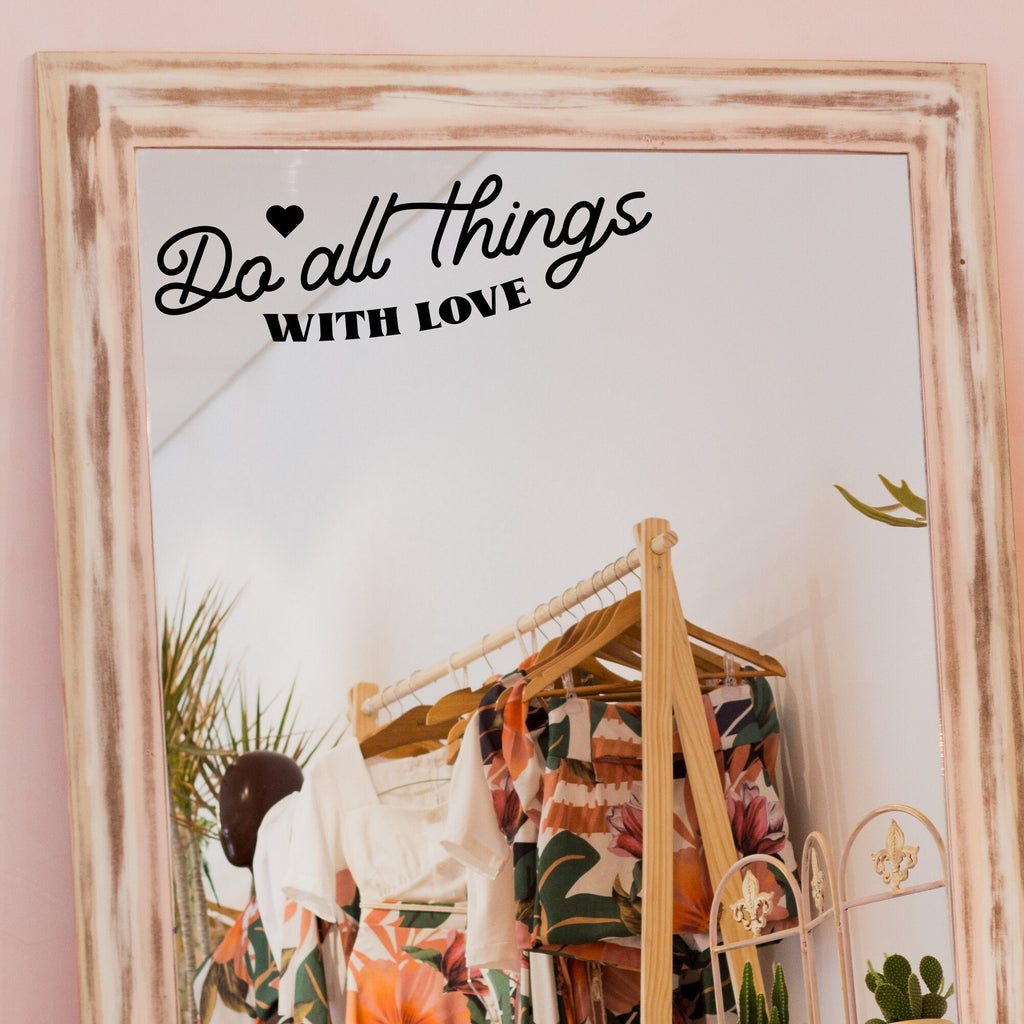 Black “Do All Things With Love” vinyl sticker on a framed dressing-room mirror