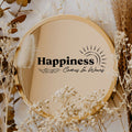 Black “Happiness Comes In Waves” vinyl sticker on a round mirror with dried flowers