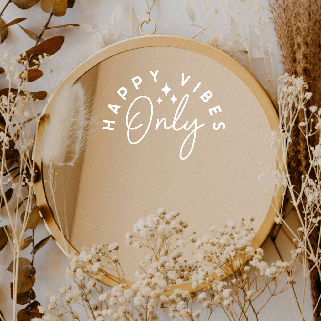 White “Happy Vibes Only” vinyl sticker on a round mirror with dried flowers