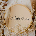 Black “I Love Us” vinyl sticker on a round mirror with dried flowers