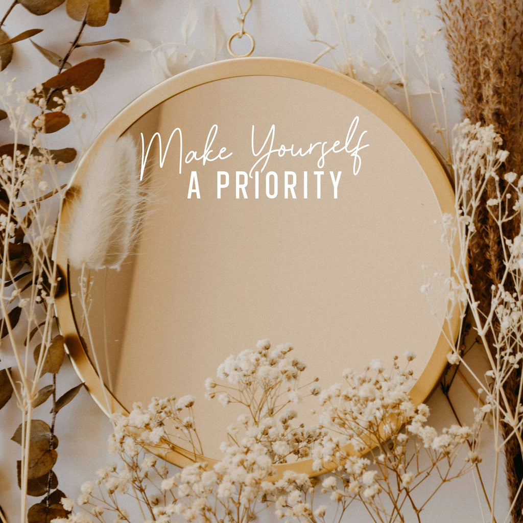 White “Make Yourself A Priority” vinyl sticker on a round mirror with dried flowers