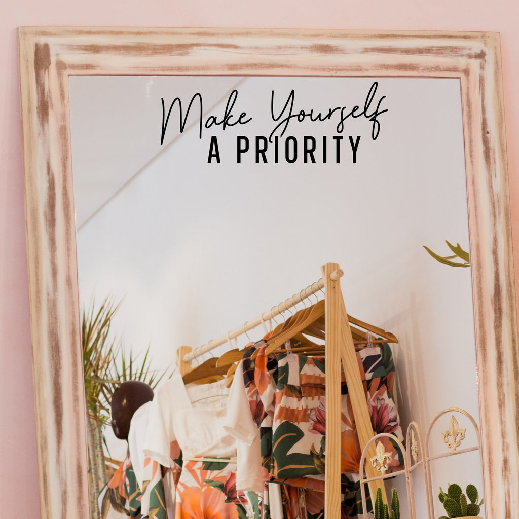 Black “Make Yourself A Priority” vinyl sticker on a framed dressing-room mirror