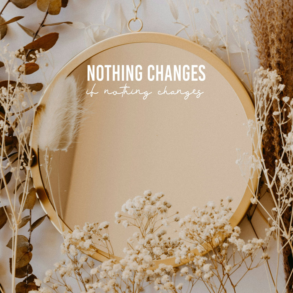 White “Nothing Changes If Nothing Changes” vinyl sticker on a round mirror with dried flowers
