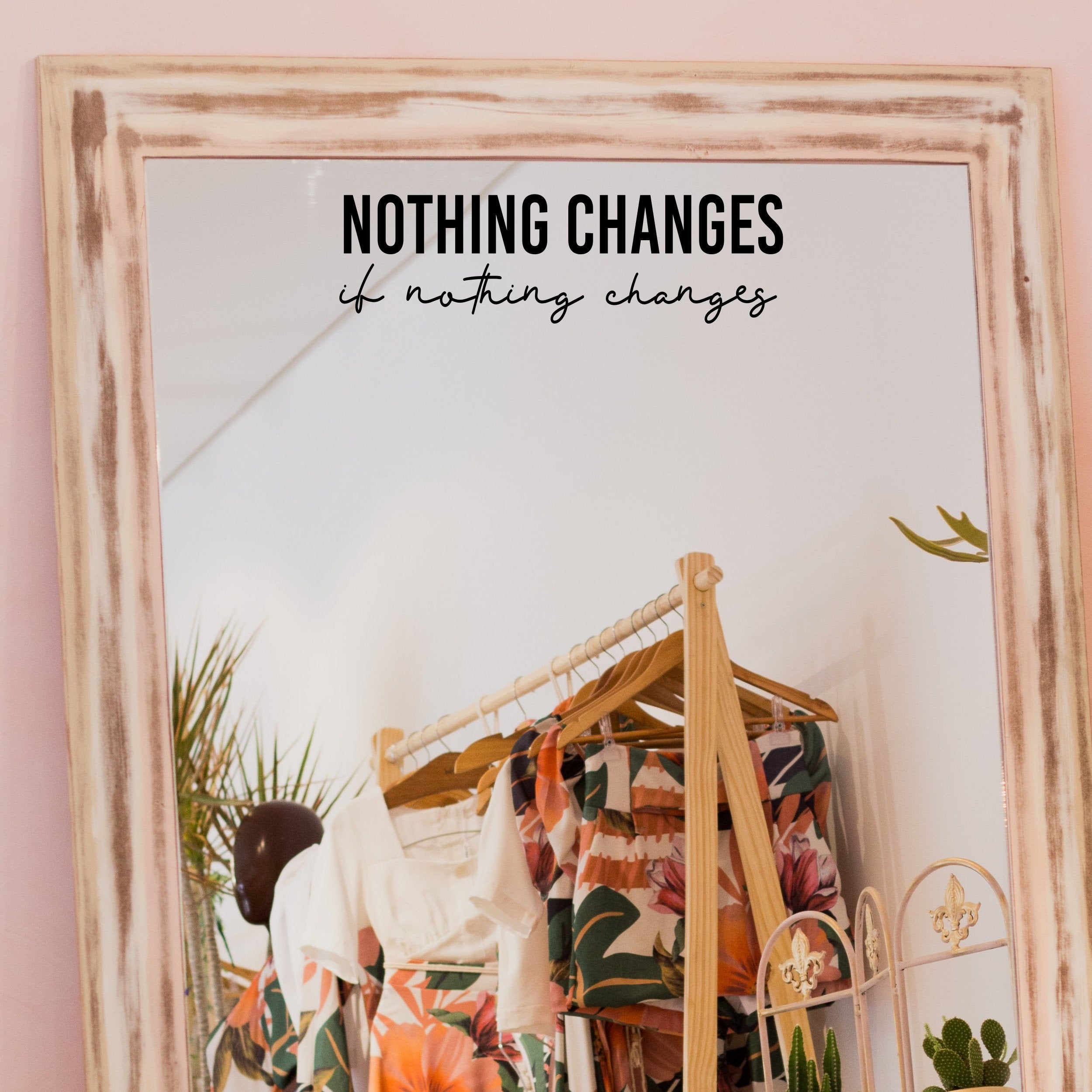 Black “Nothing Changes If Nothing Changes” vinyl sticker on a framed dressing-room mirror