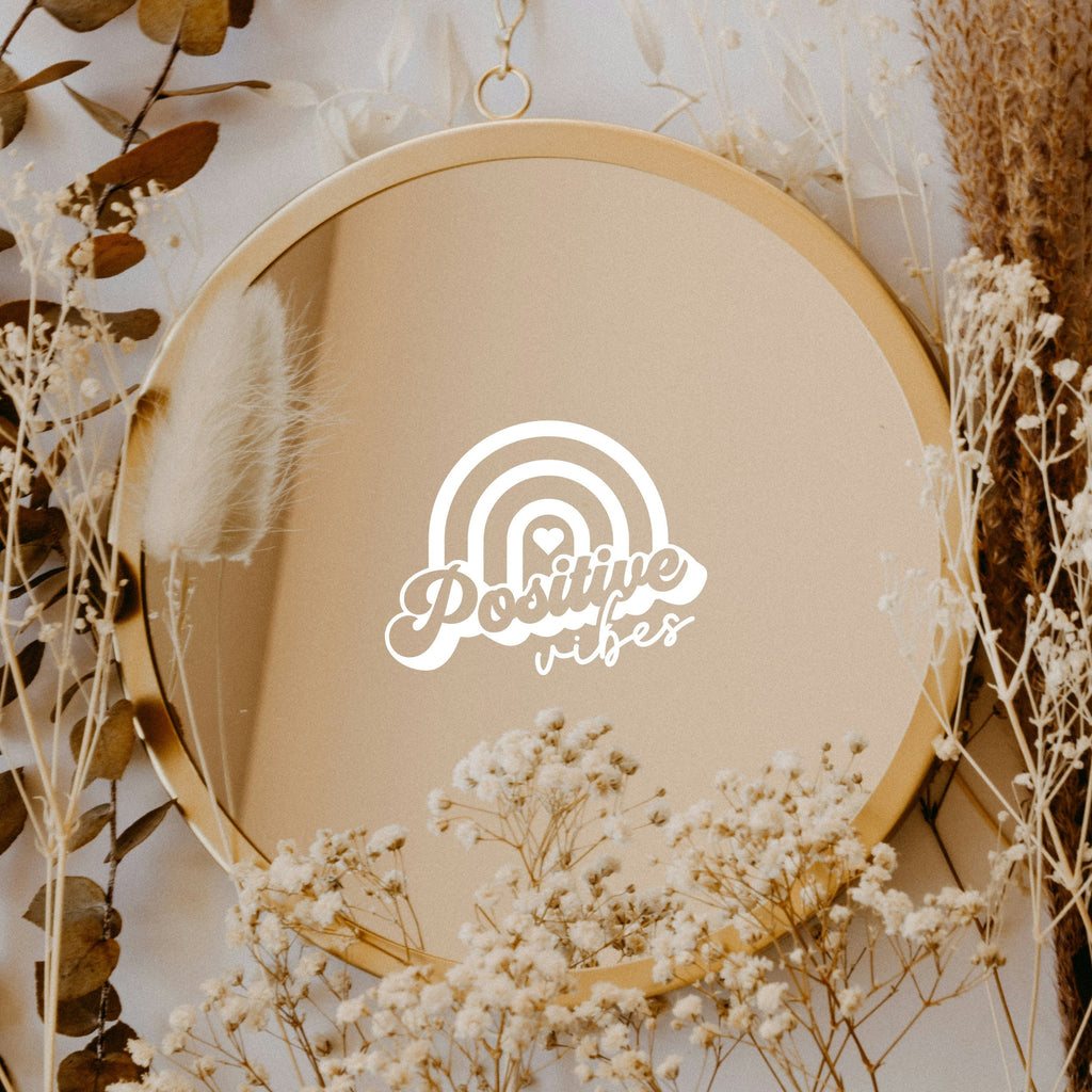 White “Positive Vibes” vinyl sticker on a round mirror with dried flowers