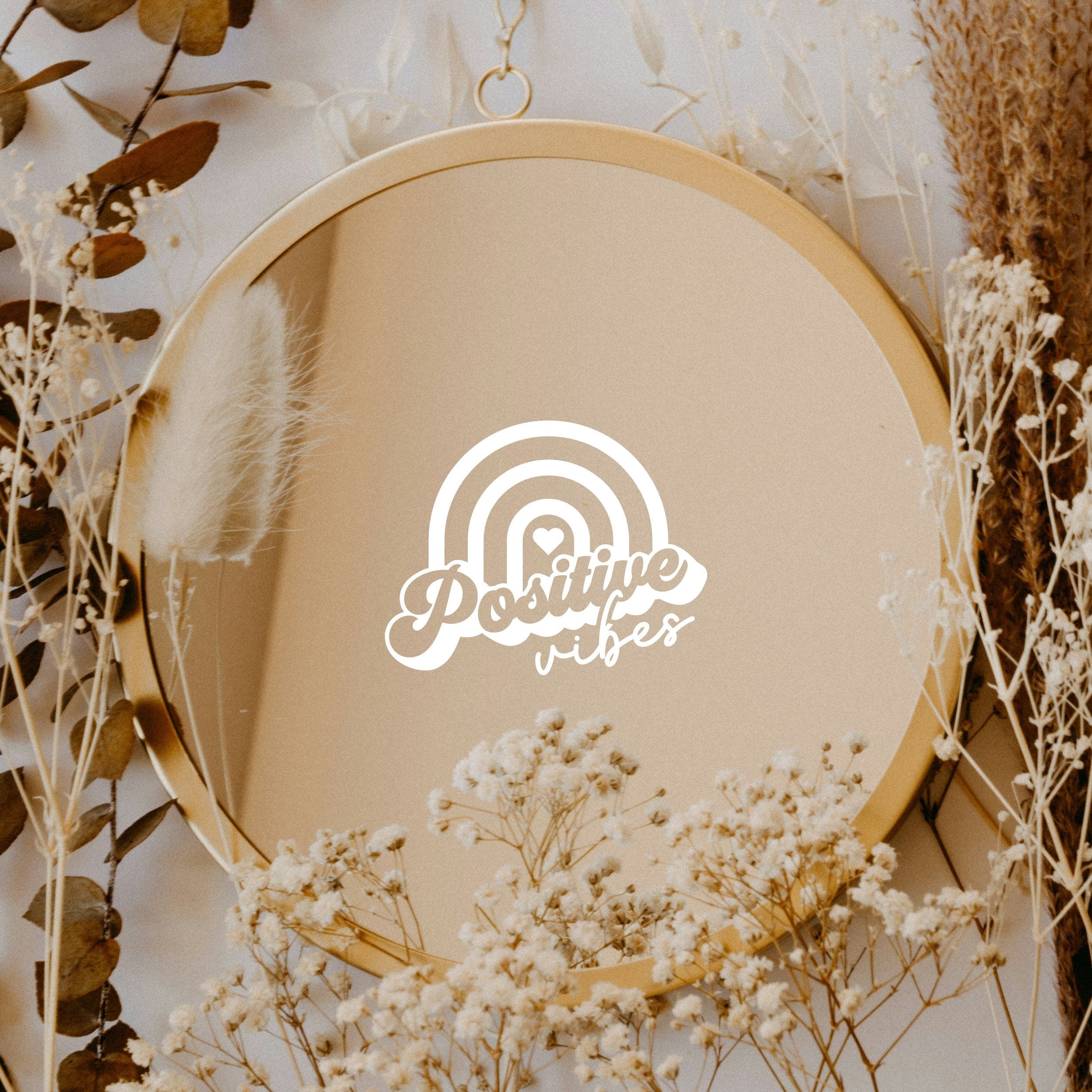 White “Positive Vibes” vinyl sticker on a round mirror with dried flowers