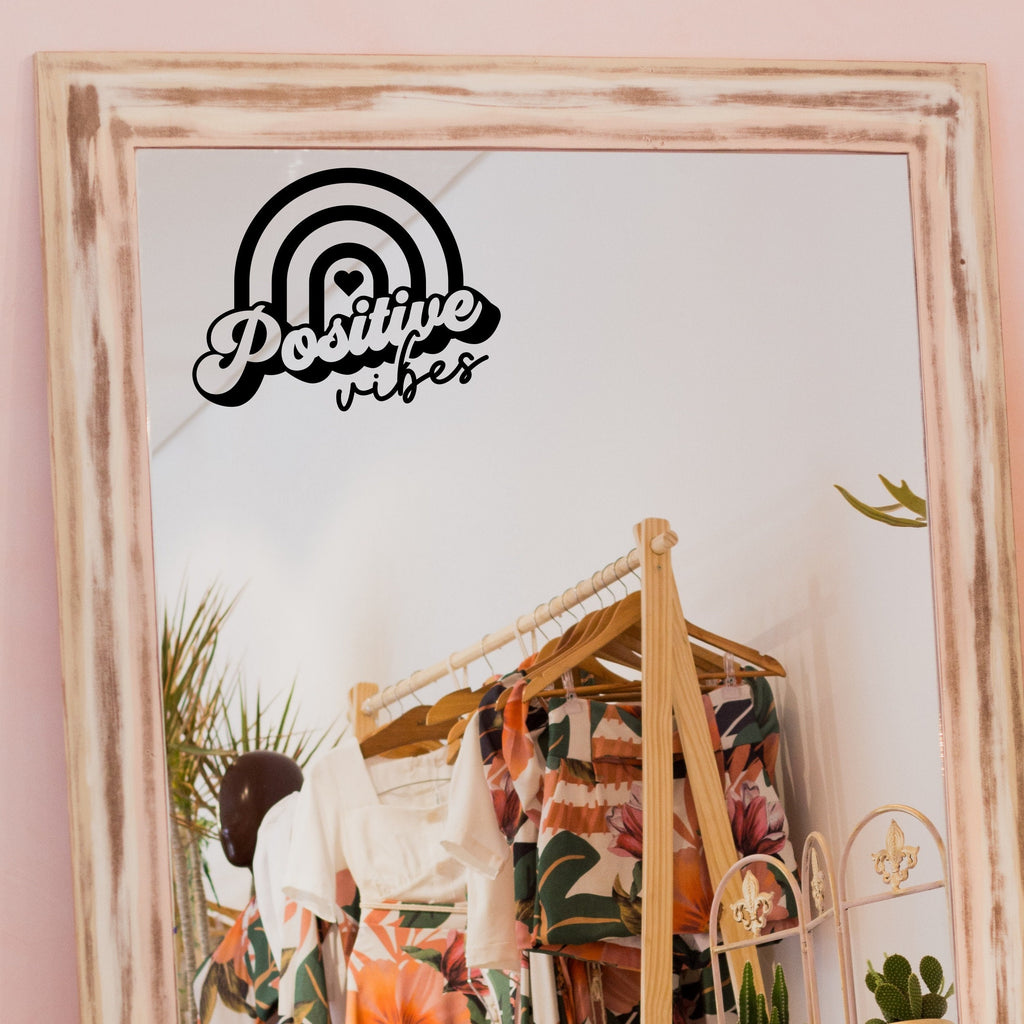 Black “Positive Vibes” vinyl sticker on a framed dressing-room mirror
