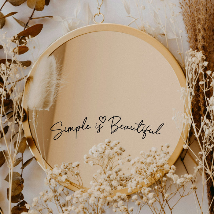 Black “Simple Is Beautiful” vinyl sticker on a round mirror with dried flowers