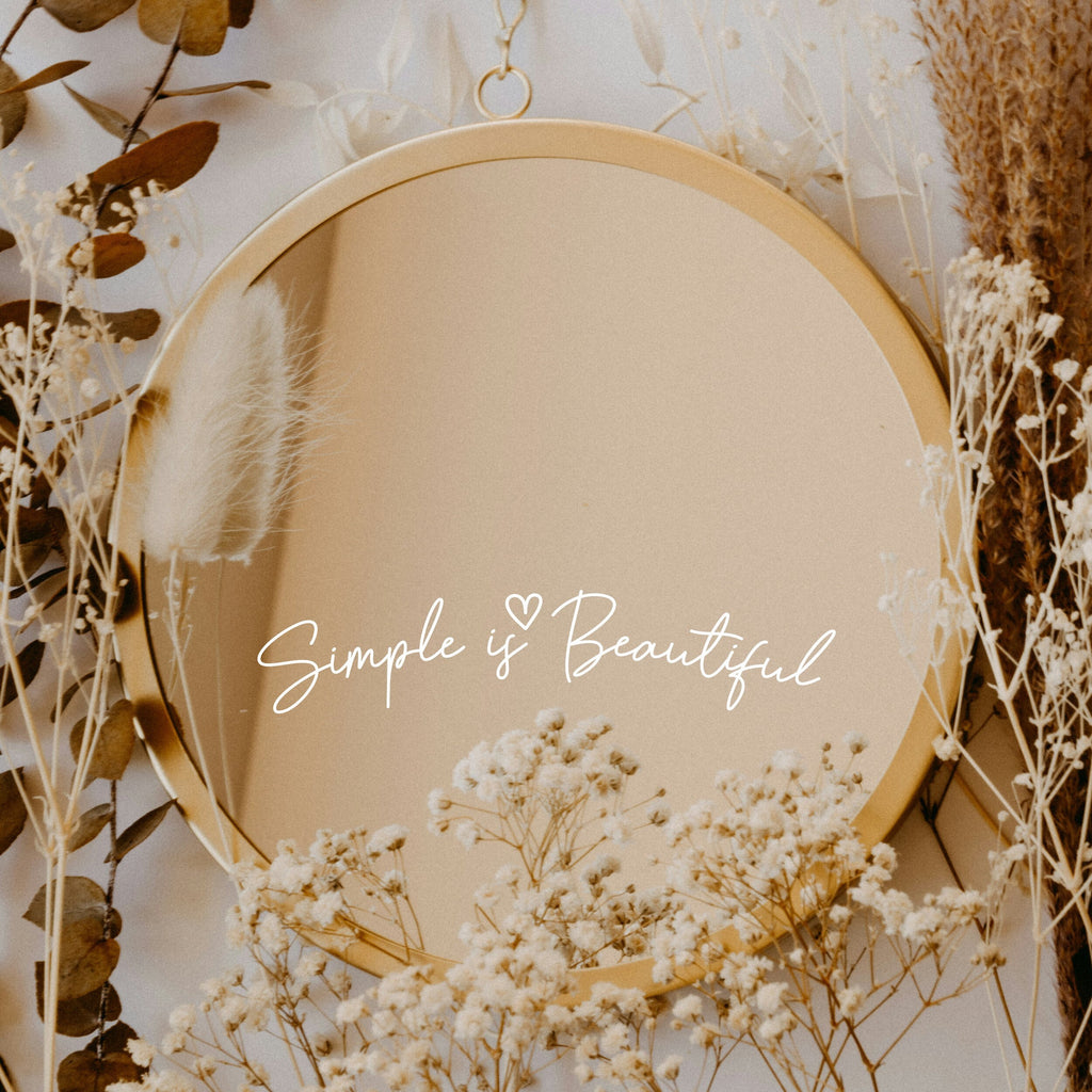 White “Simple Is Beautiful” vinyl sticker on a round mirror with dried flowers