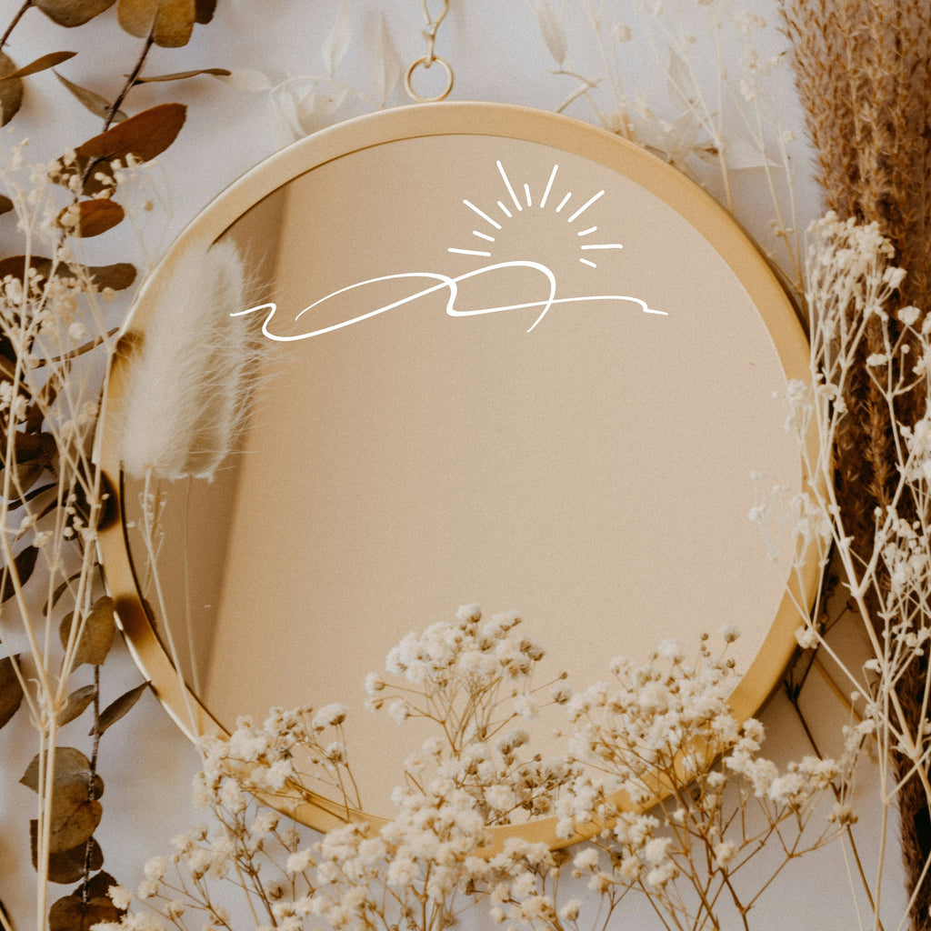 White “Sunrise” vinyl sticker on a round mirror with dried flowers