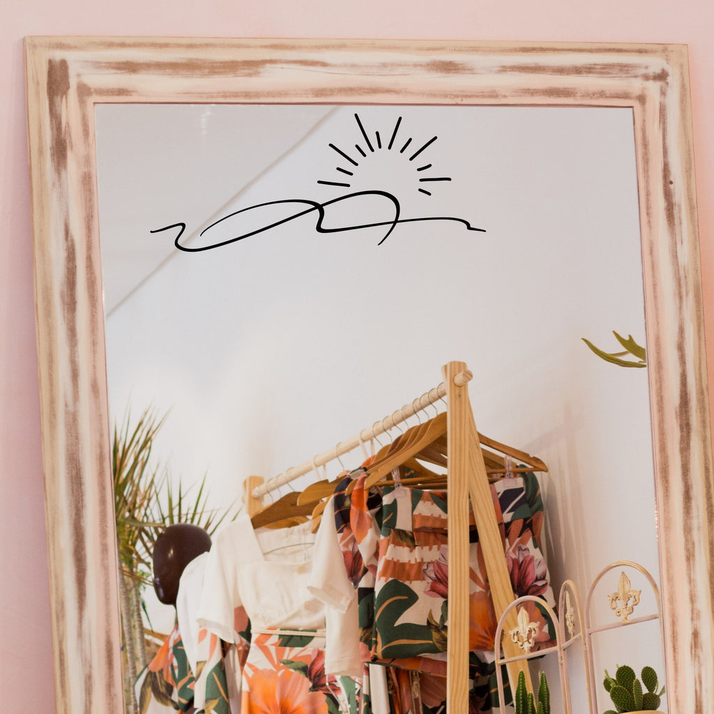 Black “Sunrise” vinyl sticker on a framed dressing-room mirror