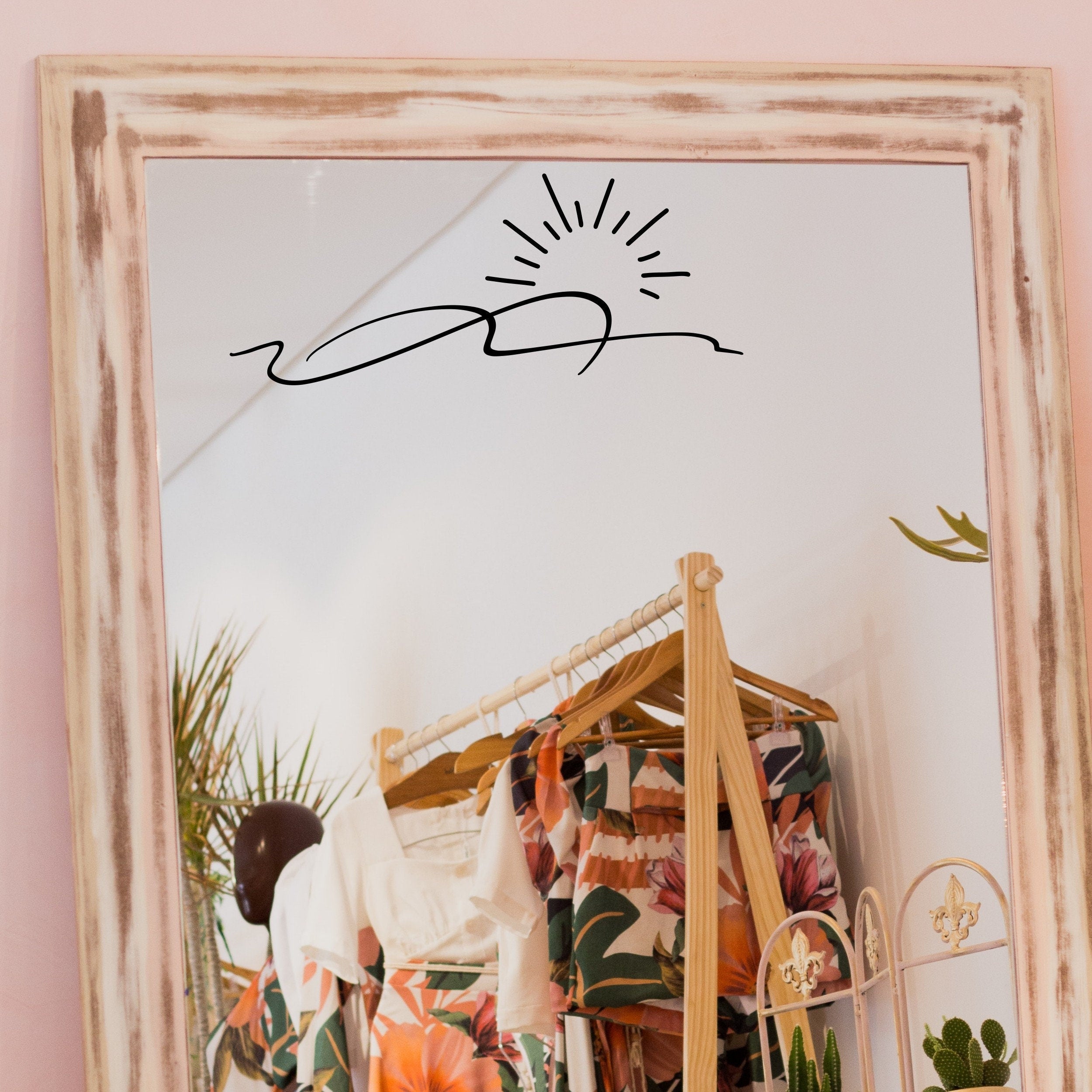Black “Sunrise” vinyl sticker on a framed dressing-room mirror