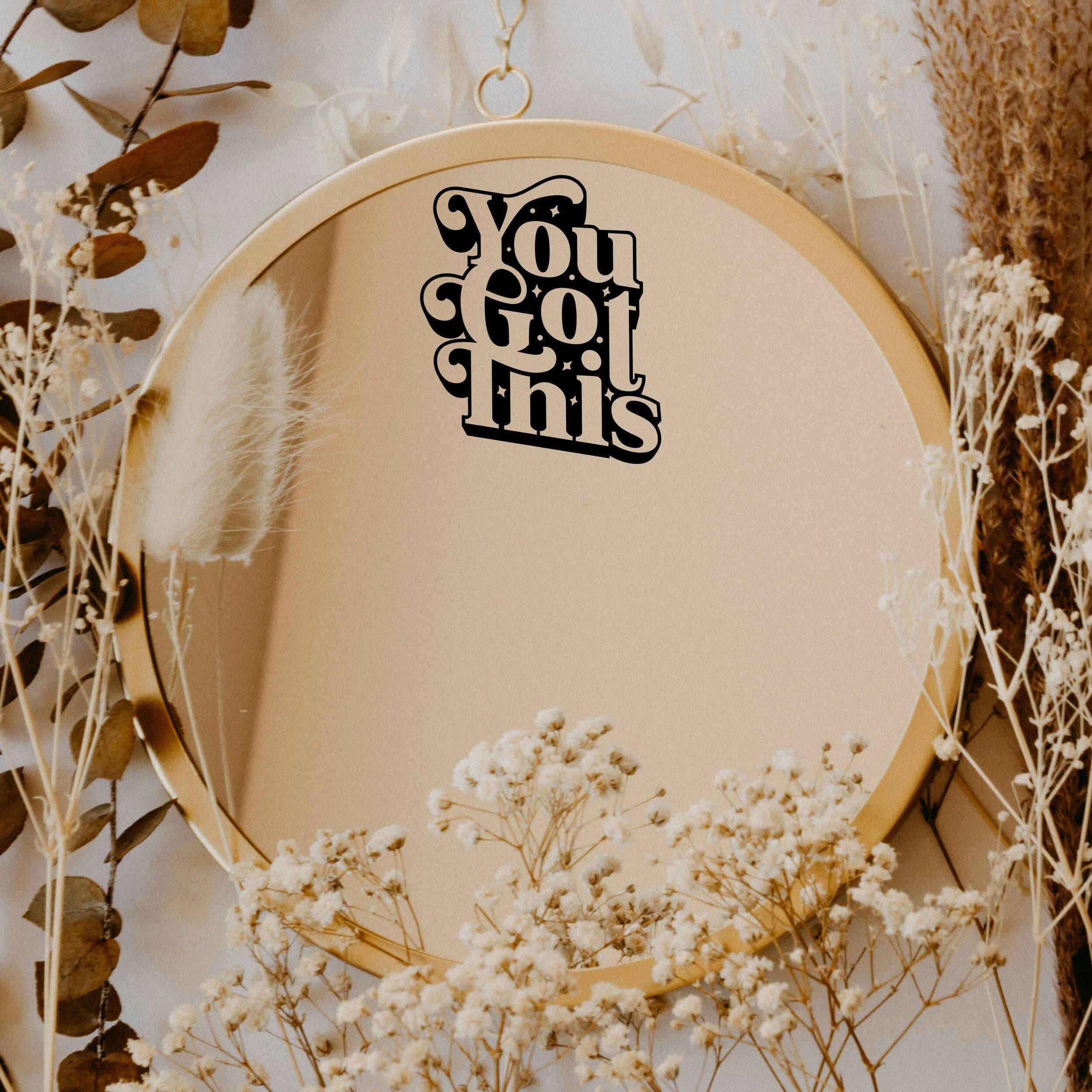 Black “You Got This” vinyl sticker on a round mirror with dried flowers