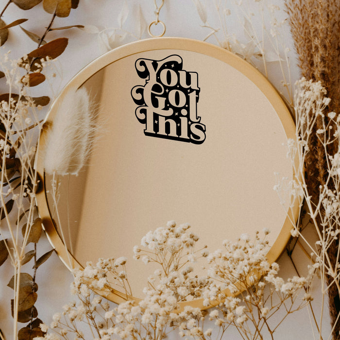 Black “You Got This” vinyl sticker on a round mirror with dried flowers