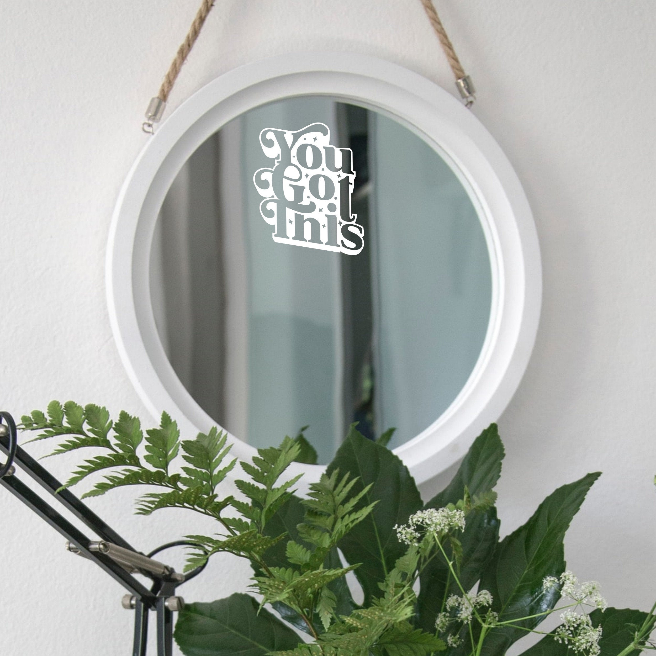 White “You Got This” mirror decal on a round white-framed mirror with green plants