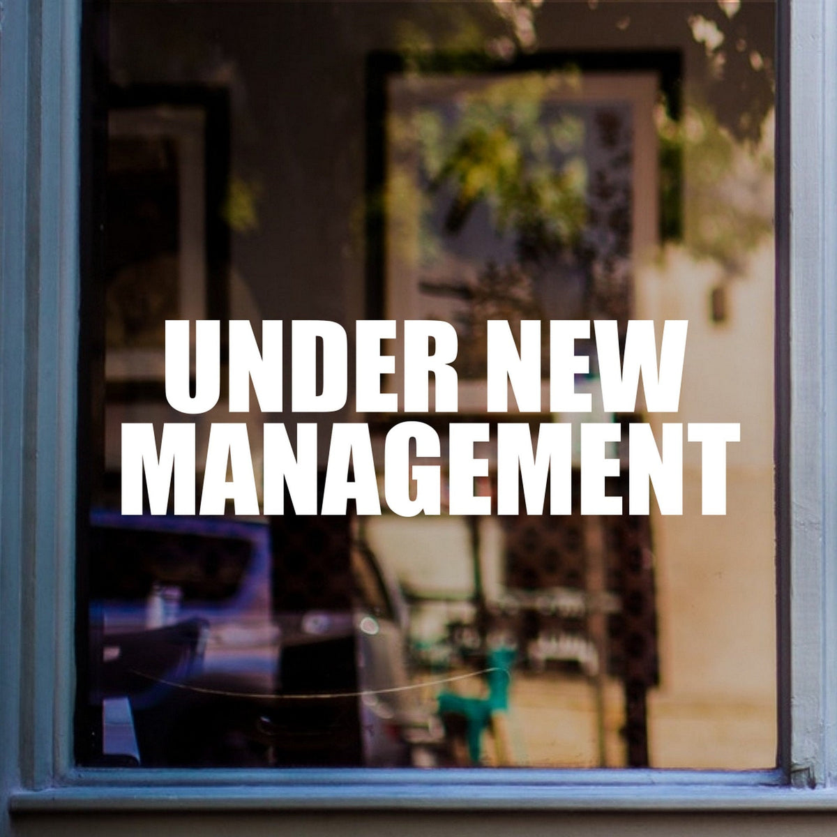 Under New Management Shop Window Sticker shown on a blue-framed shop window