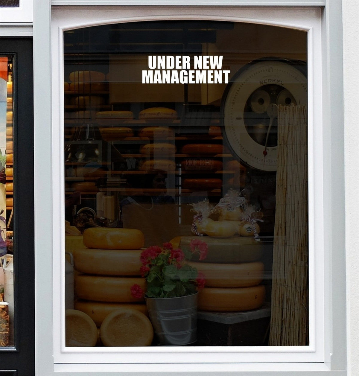 Under New Management Shop Window Sticker displayed on a storefront glass pane