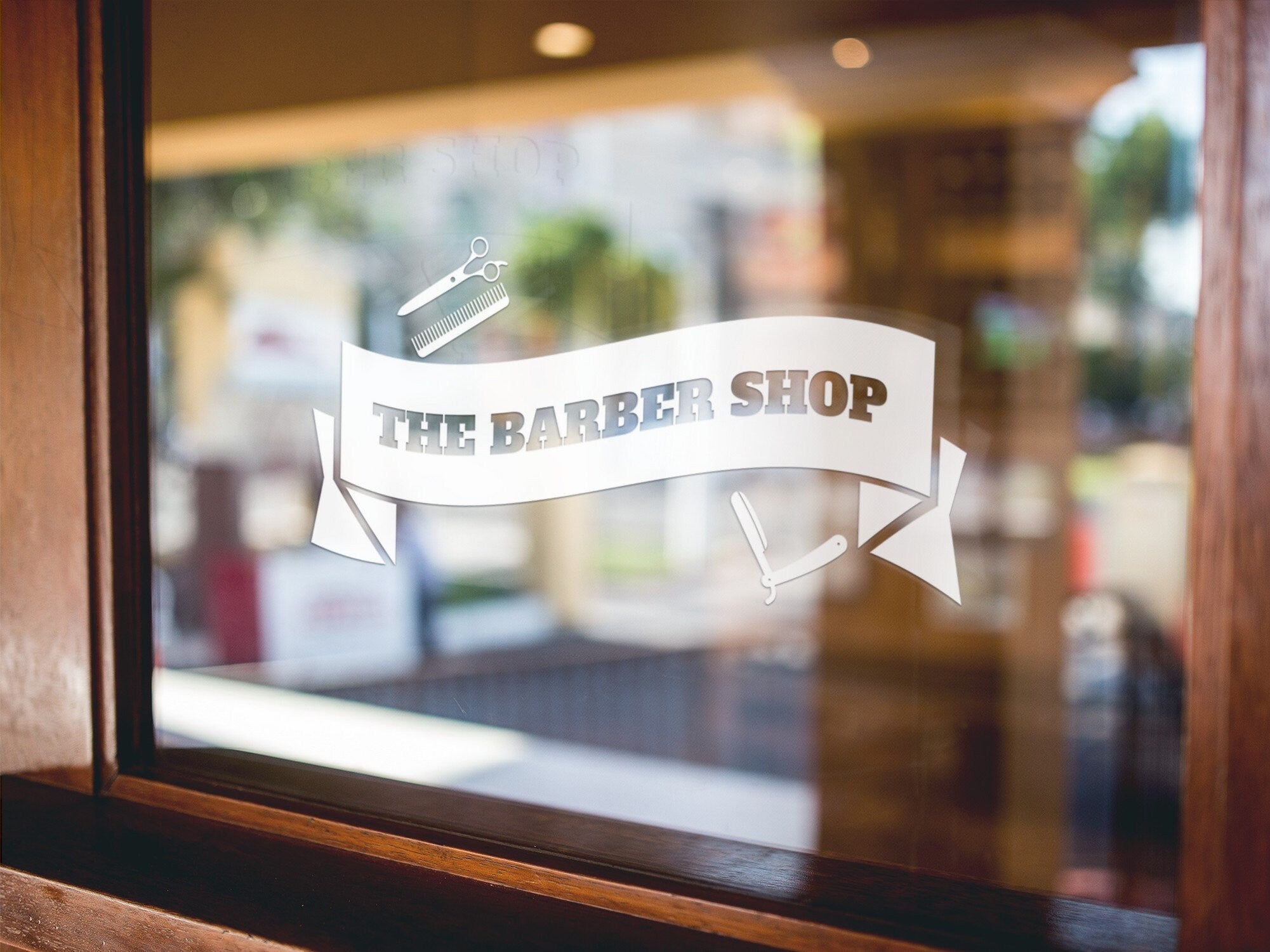 The Barber Shop Banner Window Sticker displayed on a storefront glass pane