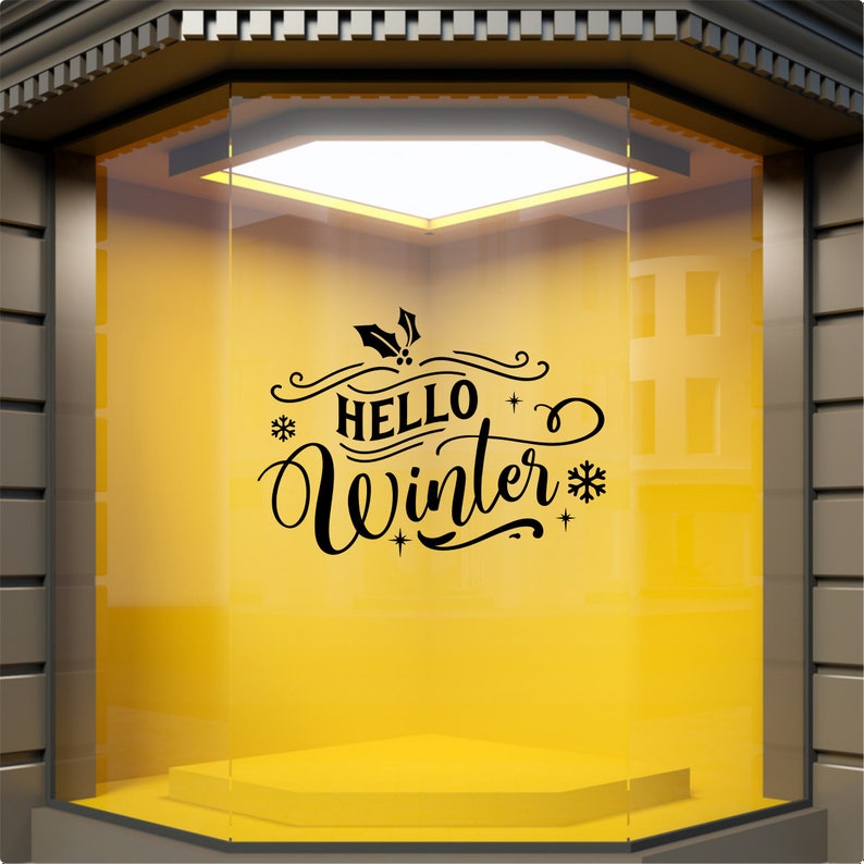 Black Hello Winter vinyl window decal displayed on a yellow shop window