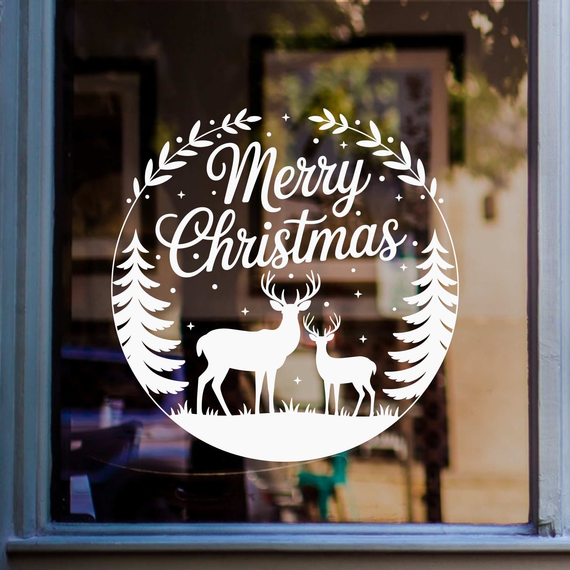A white circular Christmas window decal featuring the words 'Merry Christmas' in script, decorated with a wreath, stars, pine trees, and silhouettes of a stag and deer, shown on a window.