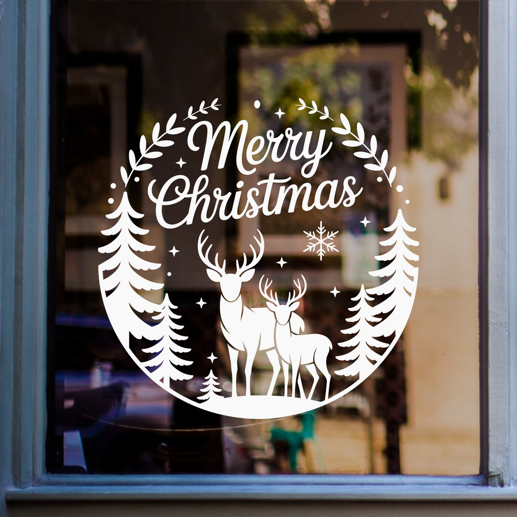 White Merry Christmas window decal featuring two deer, pine trees, and snowflakes, displayed on a glass window.