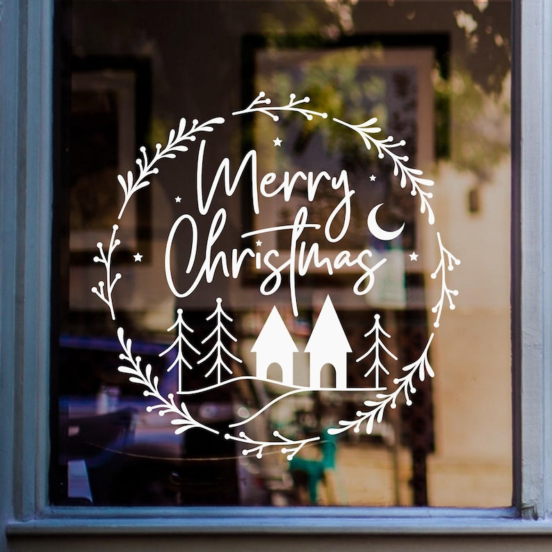 White Merry Christmas wreath window sticker with decorative fir trees displayed on a glass window.