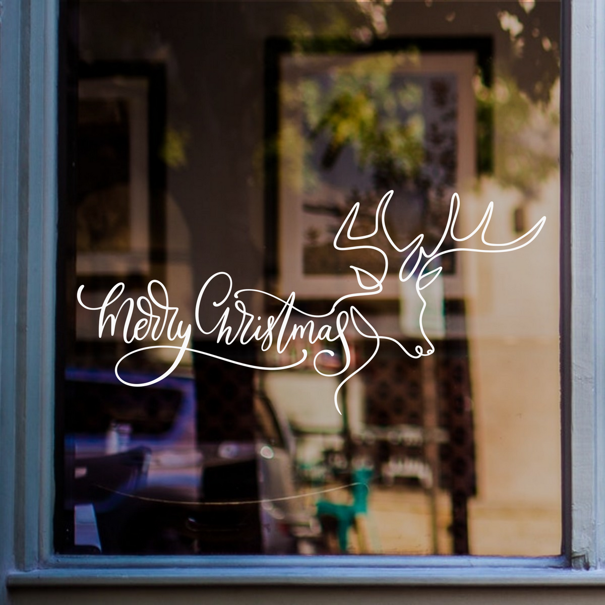 White Merry Christmas continuous-line reindeer window sticker displayed on a blue-framed shop window