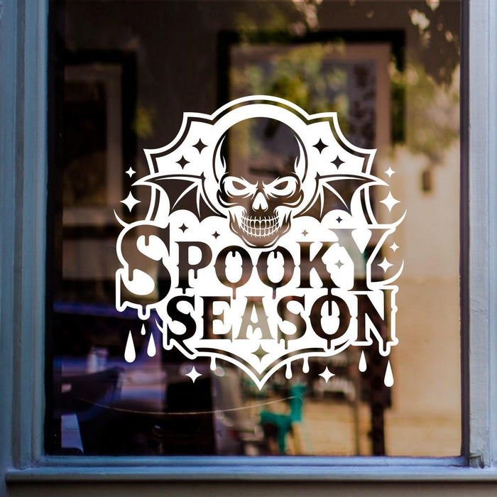 Spooky Season Skull & Bat Wings Window Sticker: white vinyl design on a blue-framed glass door