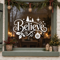 White Believe Christmas window sticker with trees, stars, holly and a snowflake bauble on a sage green framed window