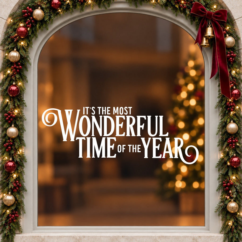 Most Wonderful Time of the Year Christmas Window Sticker in white on an arched cream window with a Christmas garland and red bow