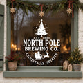 North Pole Brewing Co Christmas Window Sticker in white on a sage green framed window decorated for Christmas