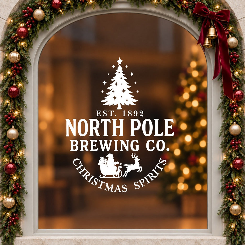 North Pole Brewing Co Christmas Window Sticker in white on an arched cream window with a Christmas garland and red bow