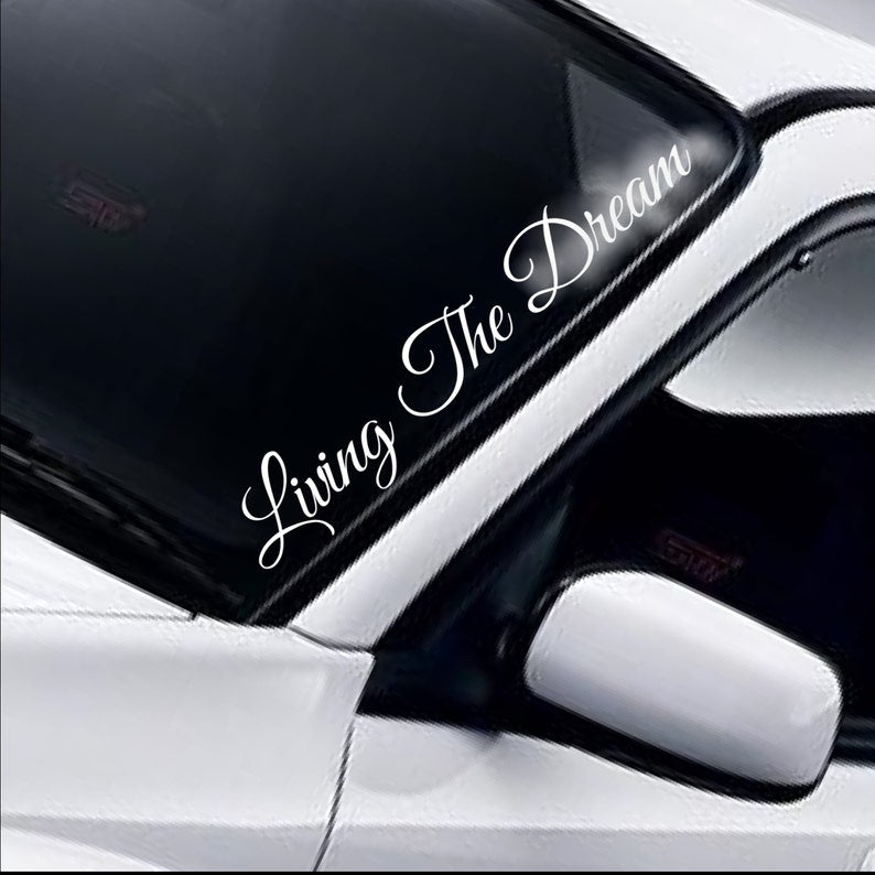 Living The Dream script white vinyl windscreen sticker fitted to a car
