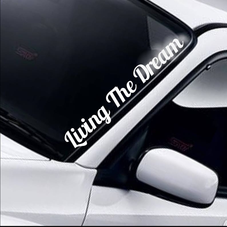 Living The Dream bold script white vinyl windscreen sticker fitted to a car