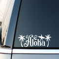 White Aloha surf sticker with palm trees on a vehicle side window.