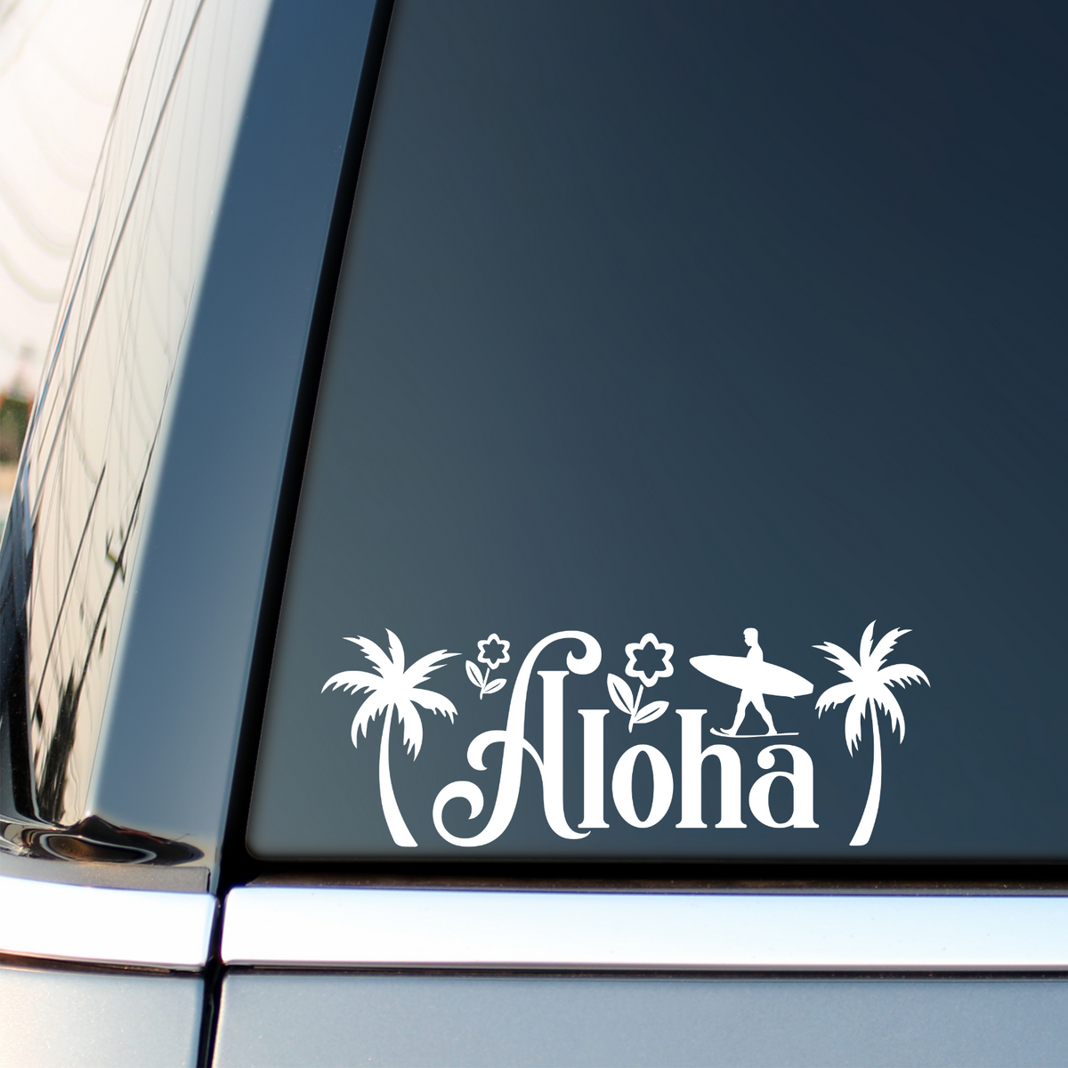 White Aloha surf sticker with palm trees on a vehicle side window.