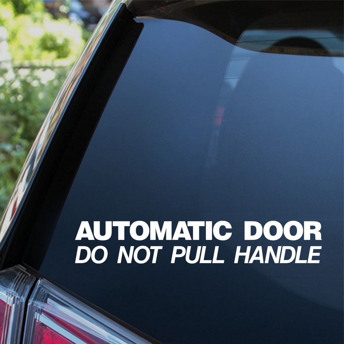 White Automatic Door Do Not Pull Handle sticker on a dark rear vehicle window.