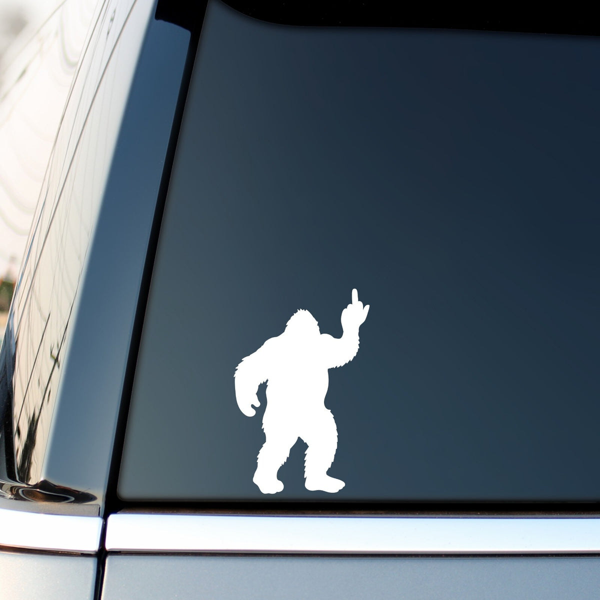 White bigfoot middle finger sticker on a vehicle side window.