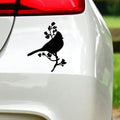 Black bird on a blossom branch sticker on white car bodywork beneath a rear light.